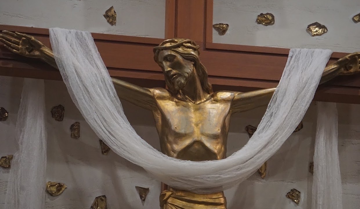 The gold crucifix above the altar, draped in white cloth